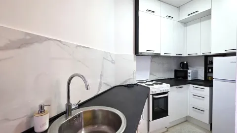 Modern kitchen with white cabinets, black countertop, and a sink in the foreground. - image 5