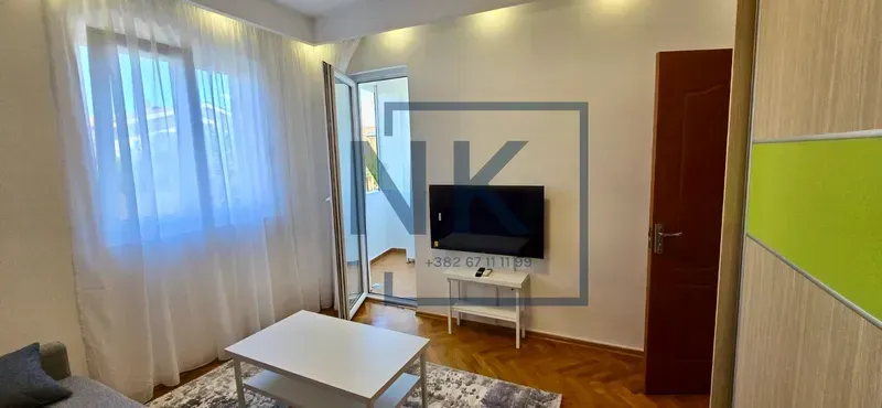Living room with a sofa, TV and access to the balcony.