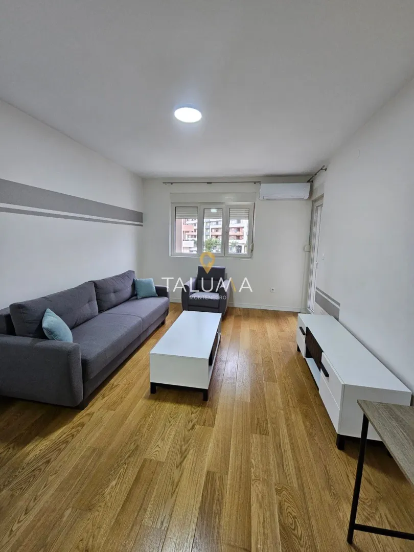 Living room furnished with a grey sofa, coffee table and TV unit.
