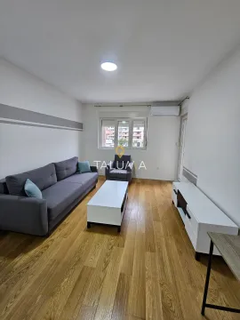 Living room furnished with a grey sofa, coffee table and TV unit. - image 2