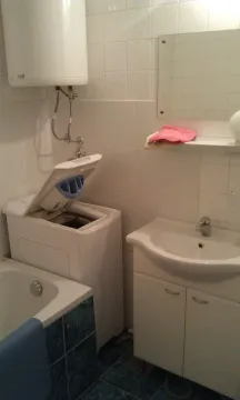 A simple bathroom with a washing machine, water heater, and sink. - image 12