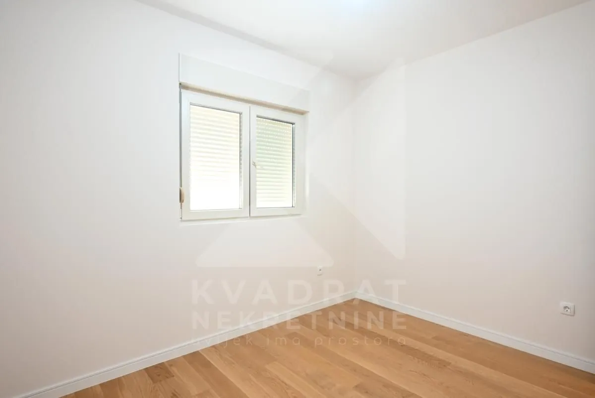 Empty room with white walls, wooden parquet flooring and a window.
