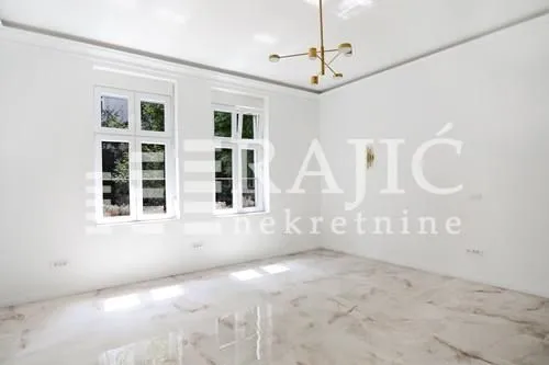 Empty bright room with windows and a modern chandelier.