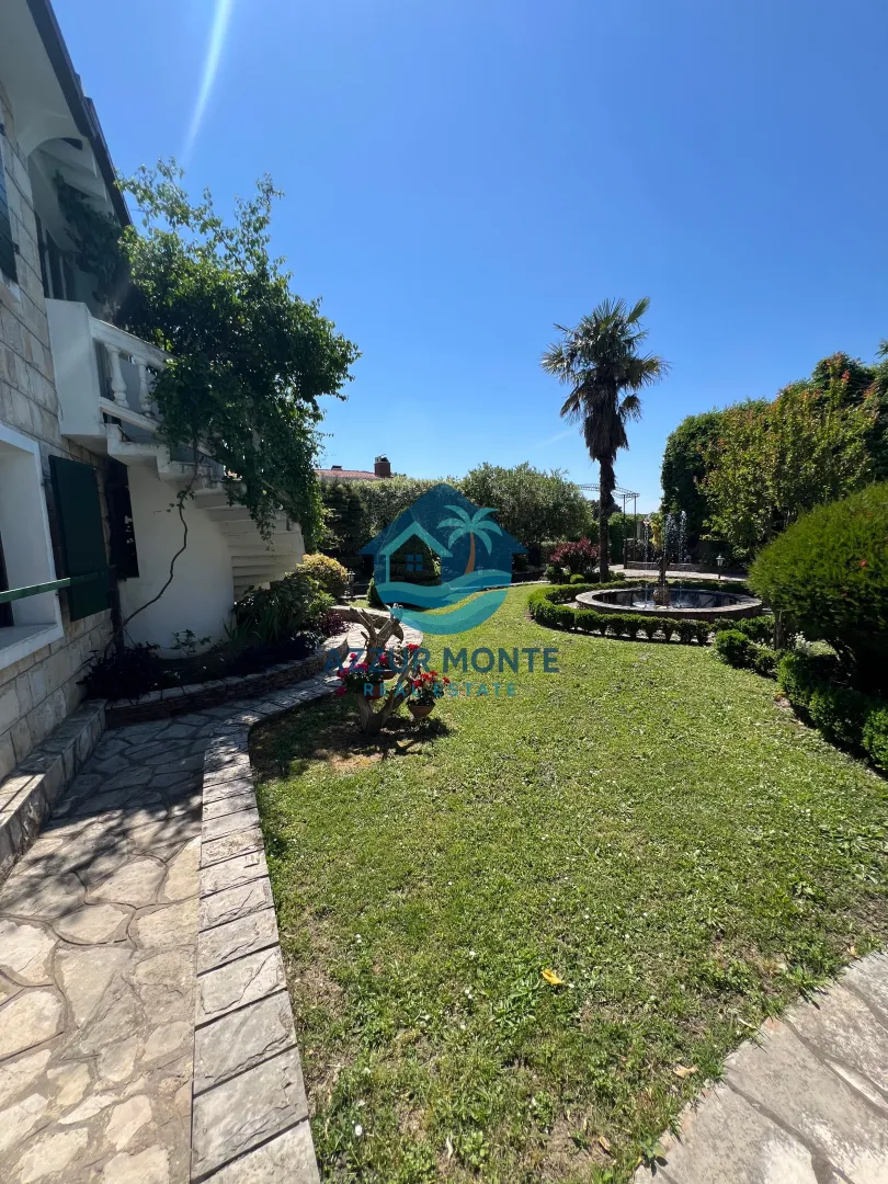 A nicely landscaped yard with greenery and a fountain next to the house.
