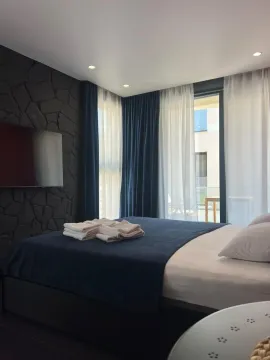 Moderna spavaća soba sa bračnim krevetom, tamnim kamenim zidom i izlazom na terasu. - image 3