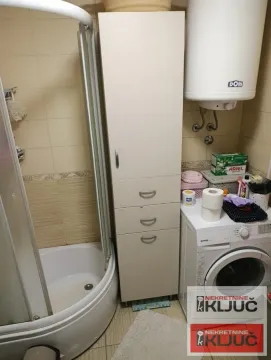 Pogled na kupatilo sa tuš kabinom, ormarićem i mašinom za veš. - image 13