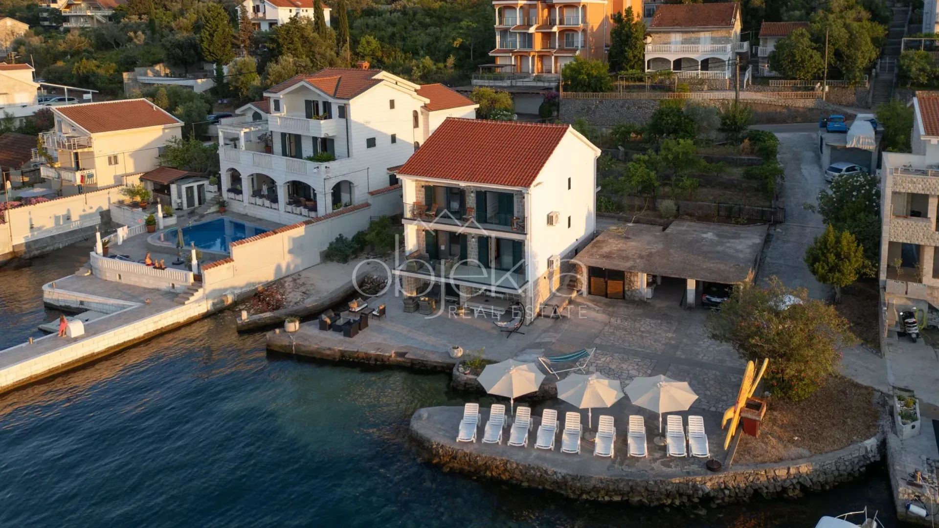 Aerial view of a seaside house with a landscaped yard and pier.