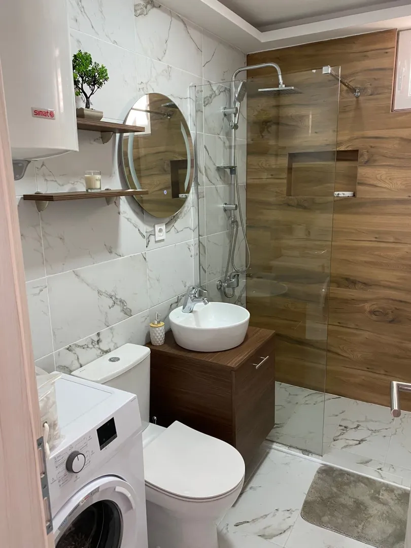 Modern bathroom with a walk-in shower, washbasin, and washing machine.