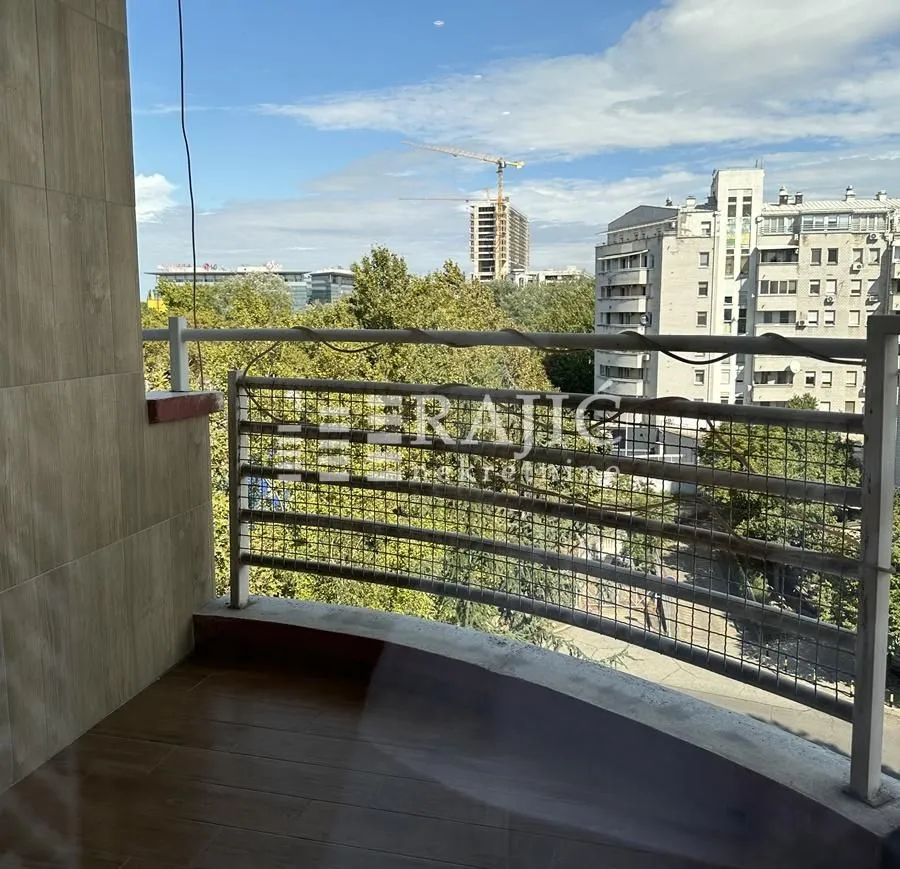 Small tiled balcony with a railing and city view.