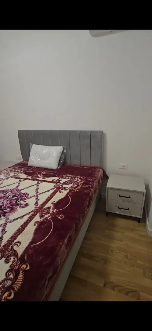 Spavaća soba sa bračnim krevetom i noćnim stočićem.