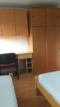 A room with two beds, a study desk, and a wooden wardrobe. - image 12