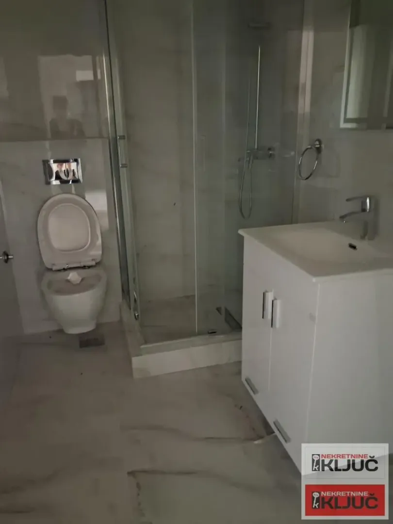 Savremeno opremljeno kupatilo sa tuš kabinom, umivaonikom i WC šoljom.