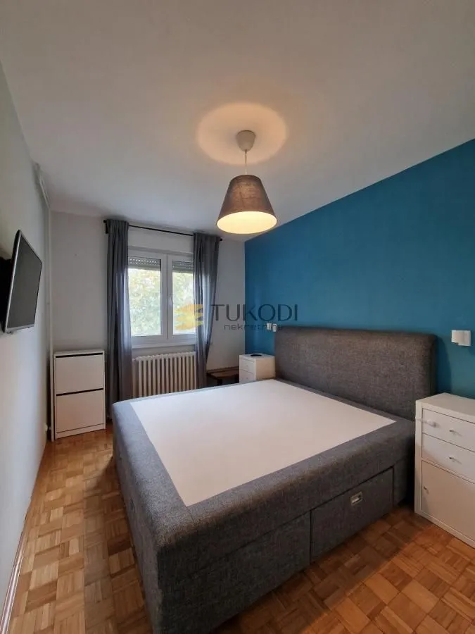 Furnished bedroom with a large double bed and a blue accent wall.