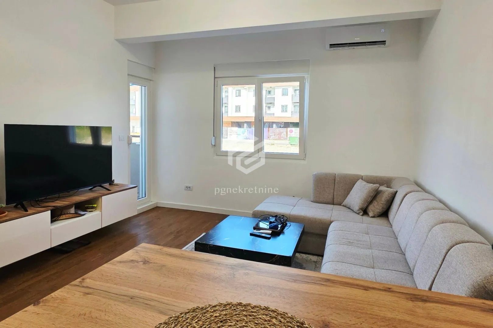 Living room with a corner sofa, television, and air conditioning unit.