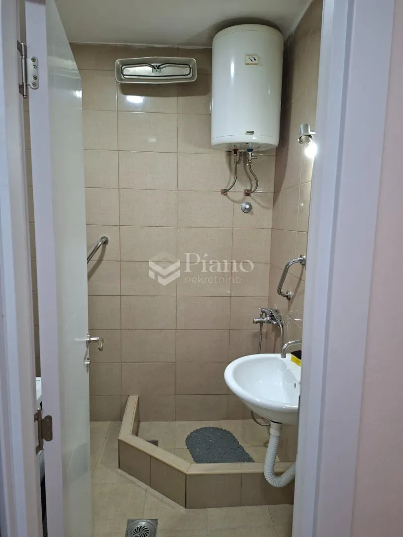 Small bathroom with a shower cabin and water heater.