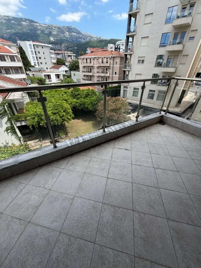 Prostrana popločana terasa sa pogledom na grad i planine.