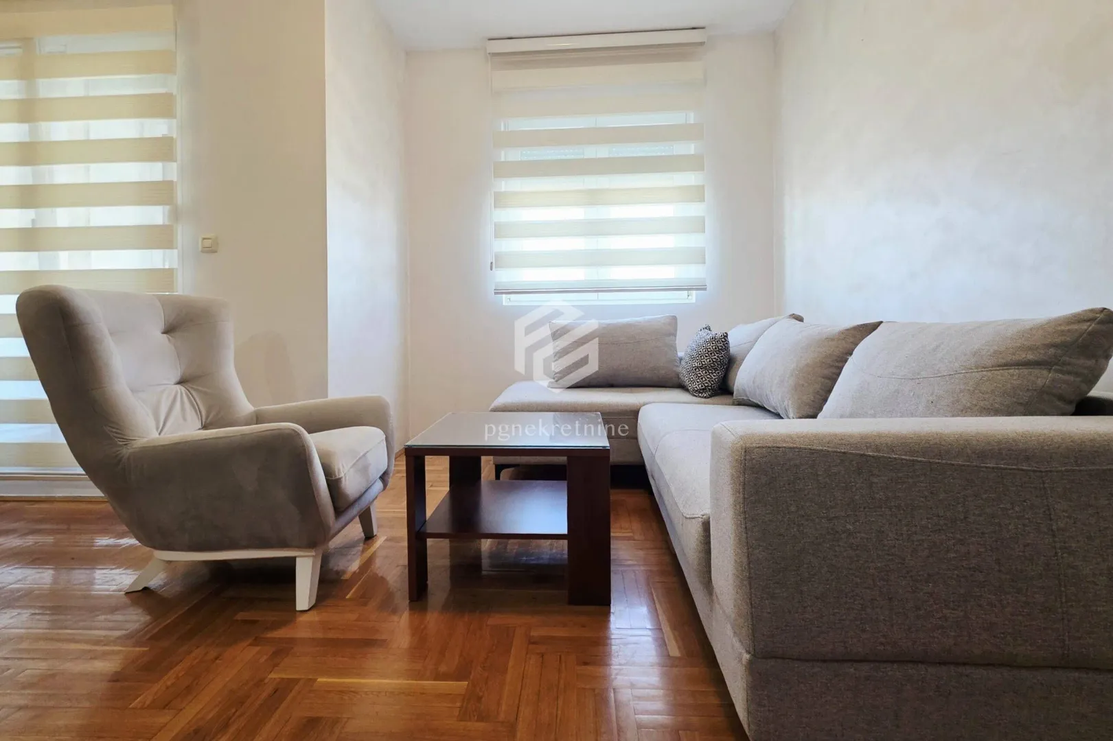 Living room with a sectional sofa, armchair, coffee table, and parquet flooring.