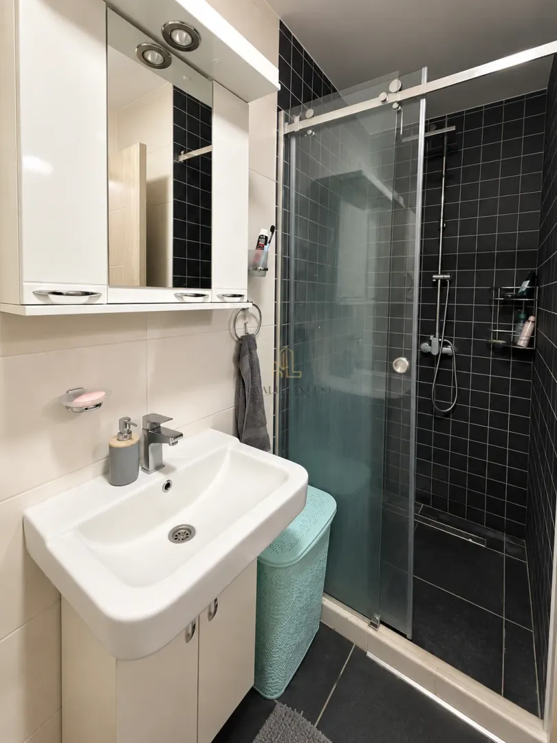 Modern bathroom with a shower cabin, washbasin, and a wall cabinet with a mirror.
