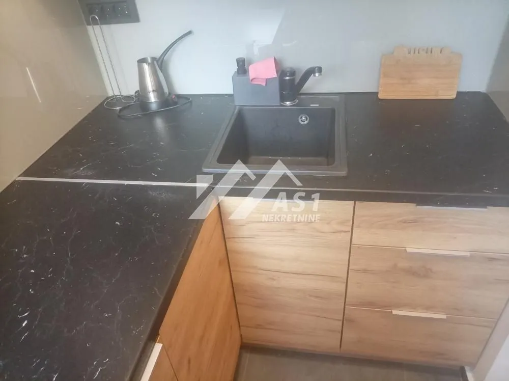 Part of the kitchen with a sink and wooden elements.