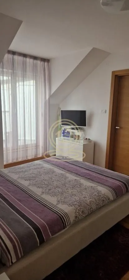 Spavaća soba sa bračnim krevetom i prozorom pod kosinom.