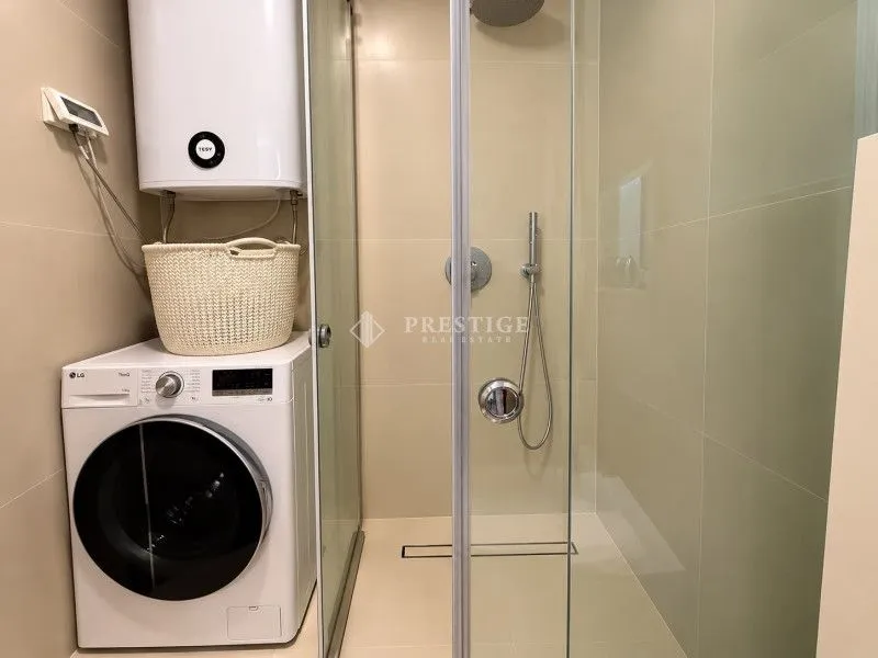 Moderno opremljeno kupatilo sa tuš kabinom i veš mašinom.
