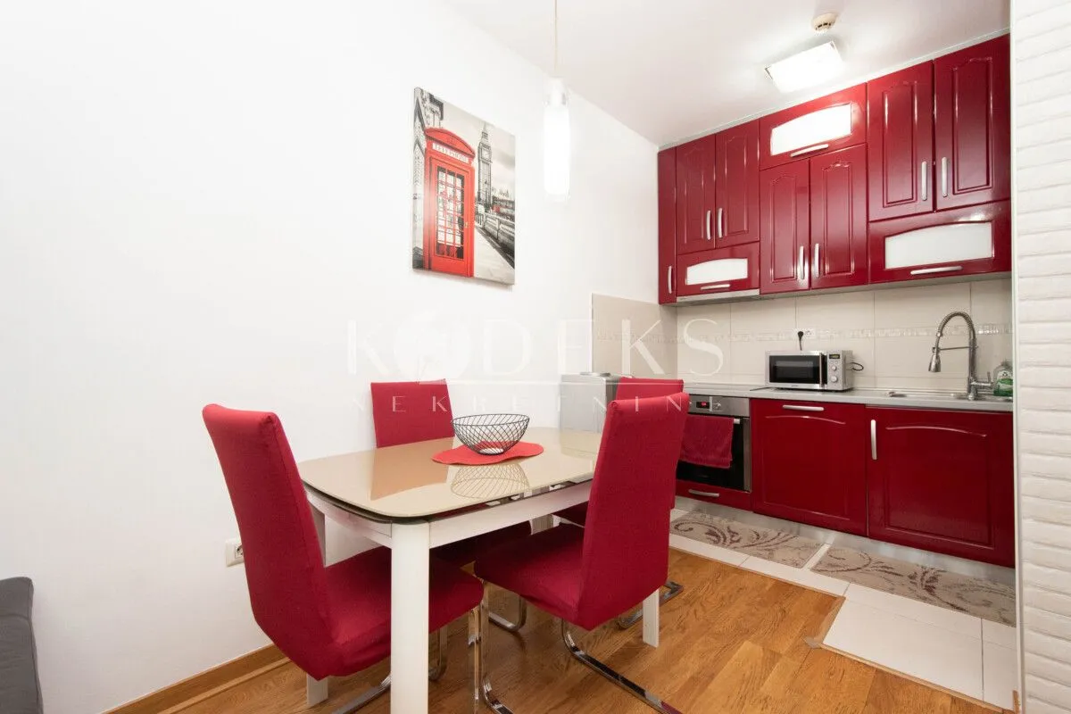 Kitchen with dining area equipped with red cabinets and a dining table.