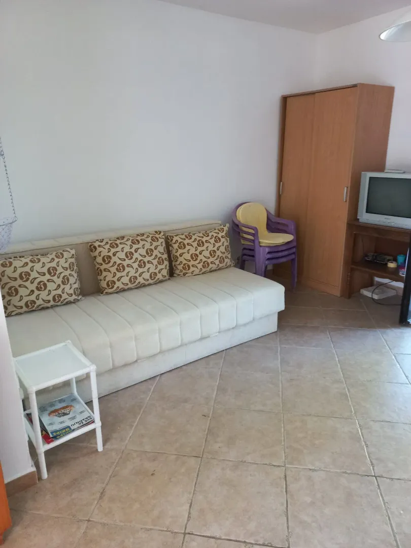 Jednostavno namješten dnevni boravak sa kaučem i ormarom.