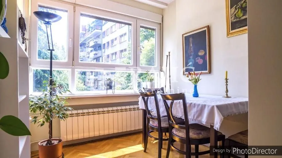Trpezarija sa trpezarijskim stolom, stolicama i velikim prozorom.