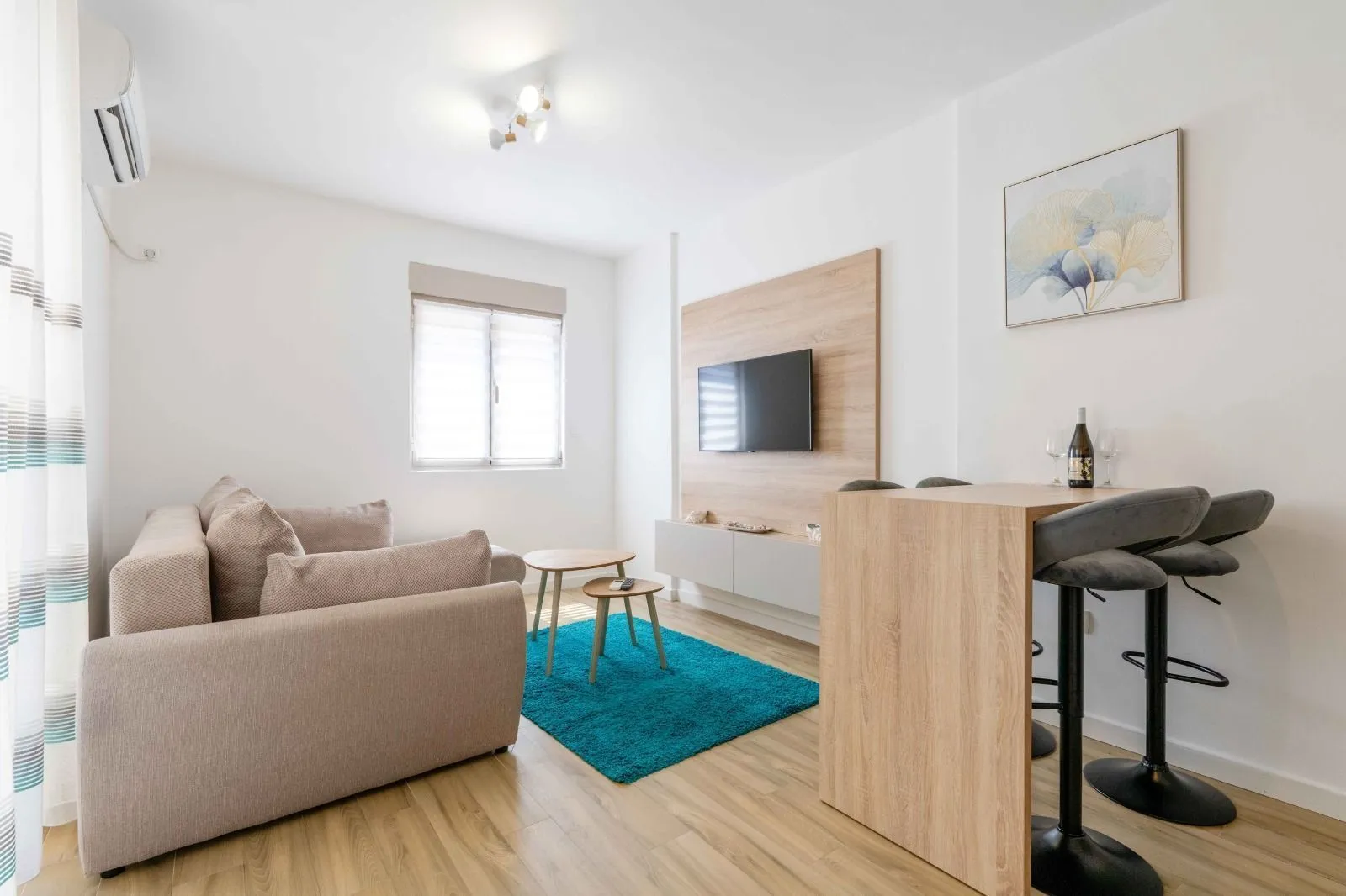 Living room with sofa, TV and a bar counter with bar stools.