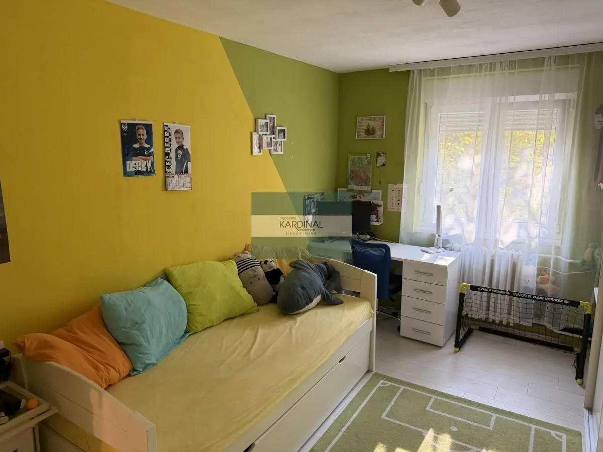 Dečja soba sa krevetom i radnim stolom pored prozora.