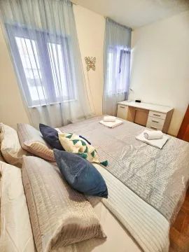 A furnished bedroom with a double bed, desk, and windows. - image 15