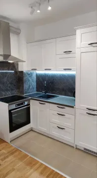 Moderna bijela kuhinja sa ugrađenim aparatima i tamnom radnom površinom. - image 7