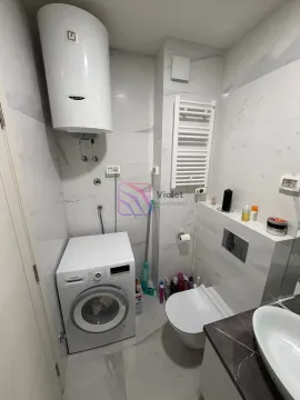Kompaktno kupatilo sa bijelim pločicama, wc šoljom, umivaonikom, veš mašinom i bojlerom. - image 9