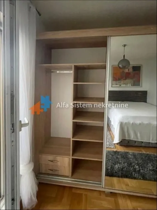 Large wooden wardrobe with sliding doors and a mirror in the bedroom.