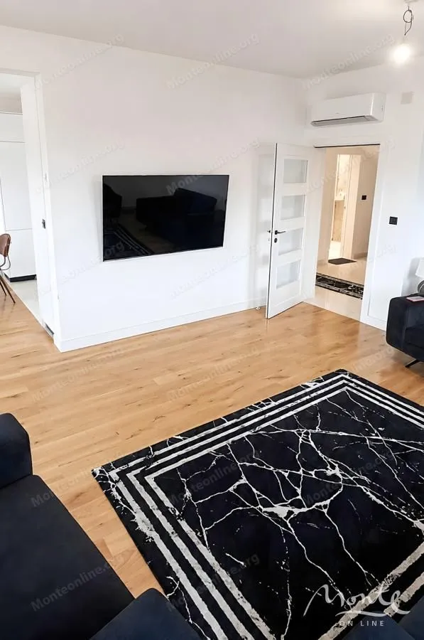 Living room with a sofa, wall-mounted TV, and air conditioning unit.