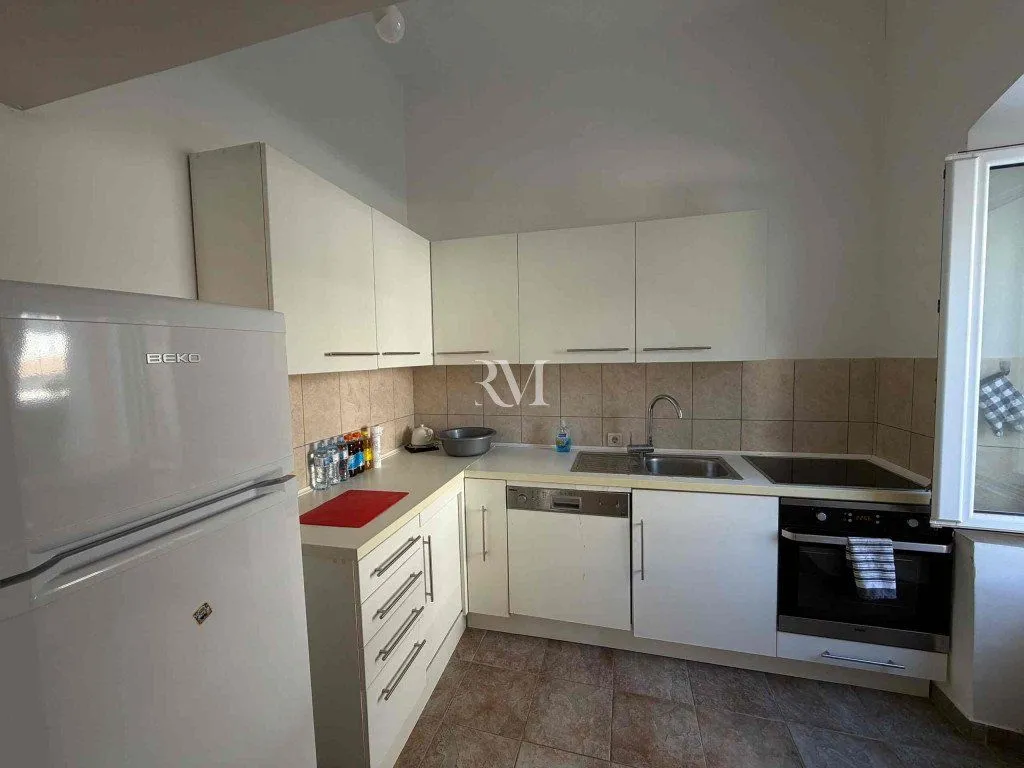 Smaller white kitchen with a refrigerator and built-in appliances.