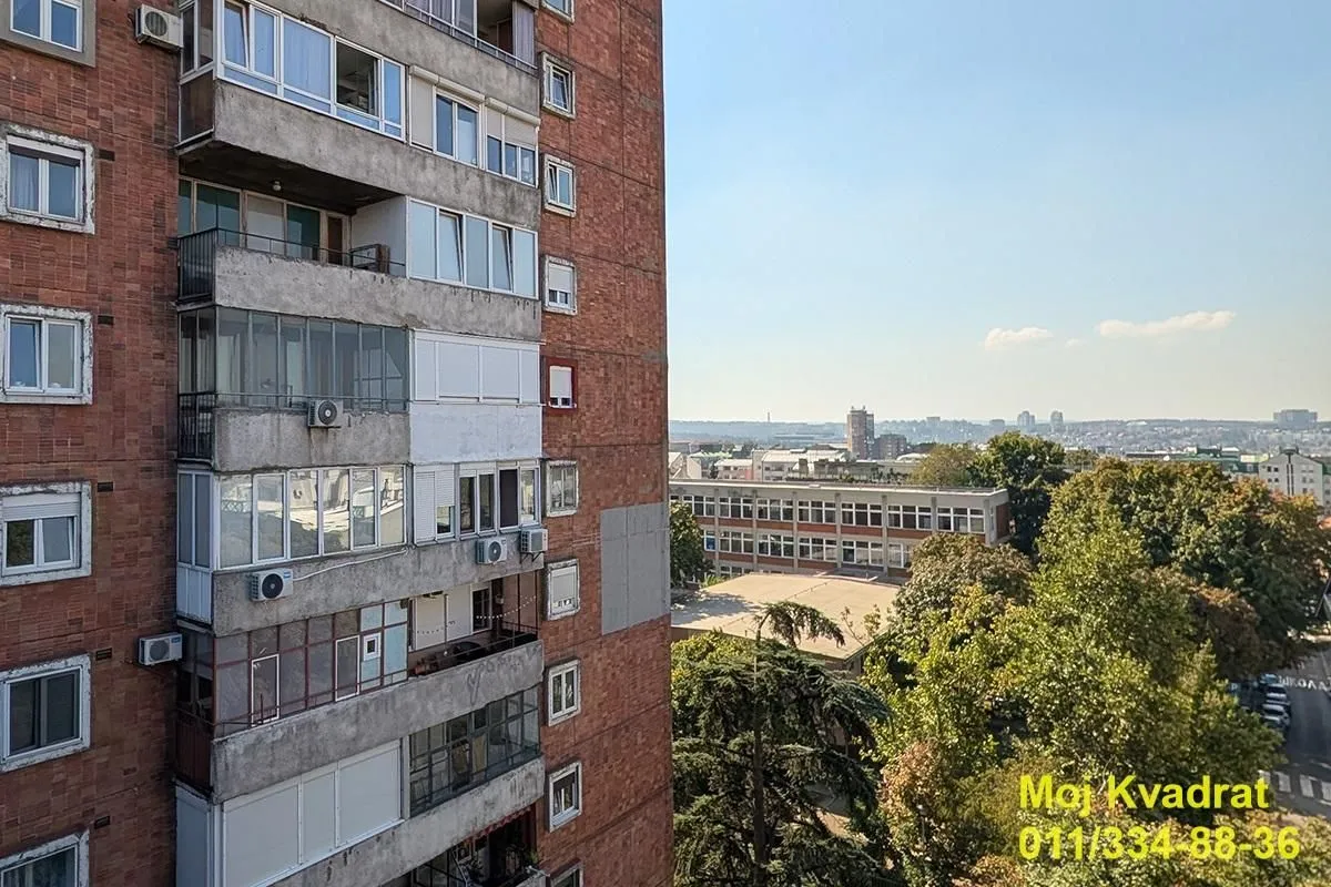 Pogled sa prozora na okolne zgrade i gradski pejzaž.