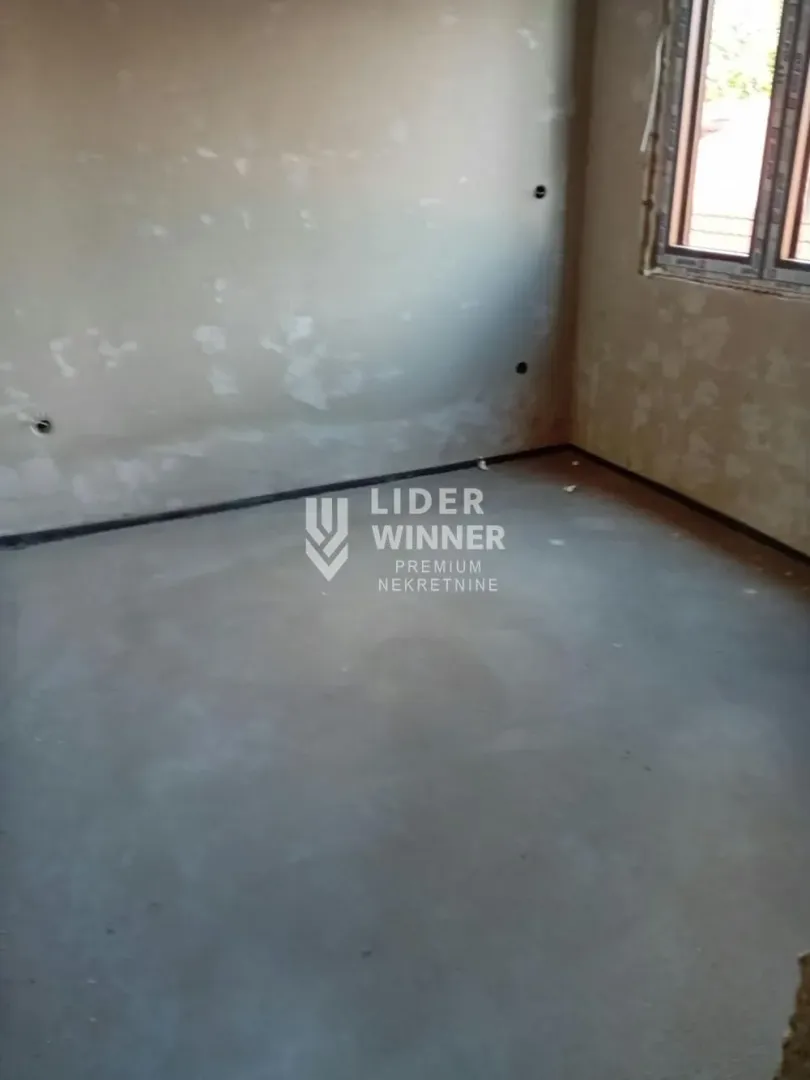 View of an unfinished room in the rough construction phase with a window.