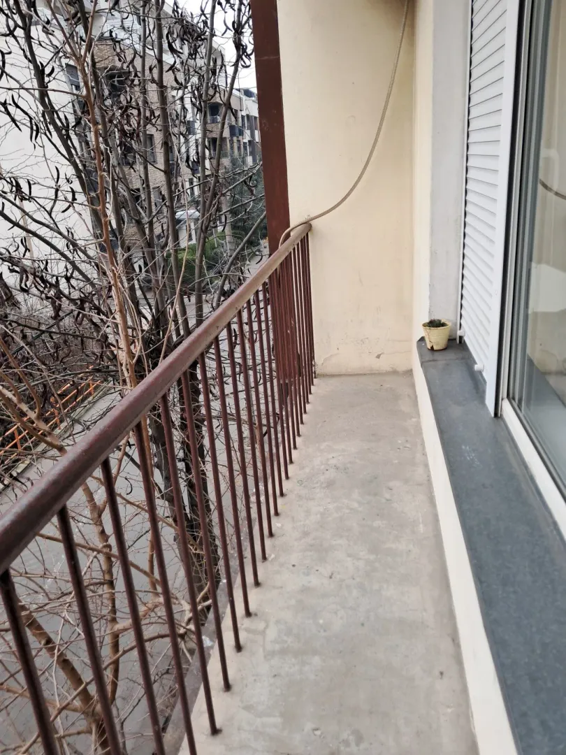 Manji balkon sa metalnom ogradom i pogledom na ulicu.