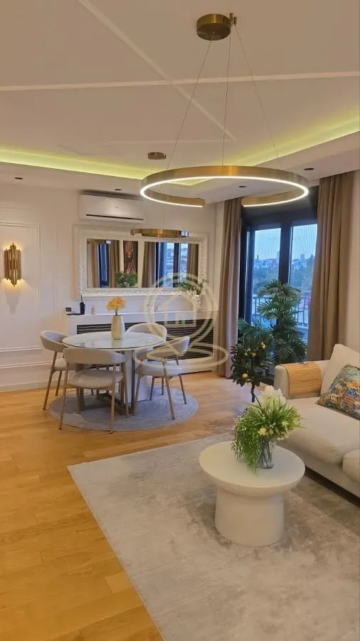 Prostrani dnevni boravak sa trpezarijskim delom i modernim osvetljenjem.