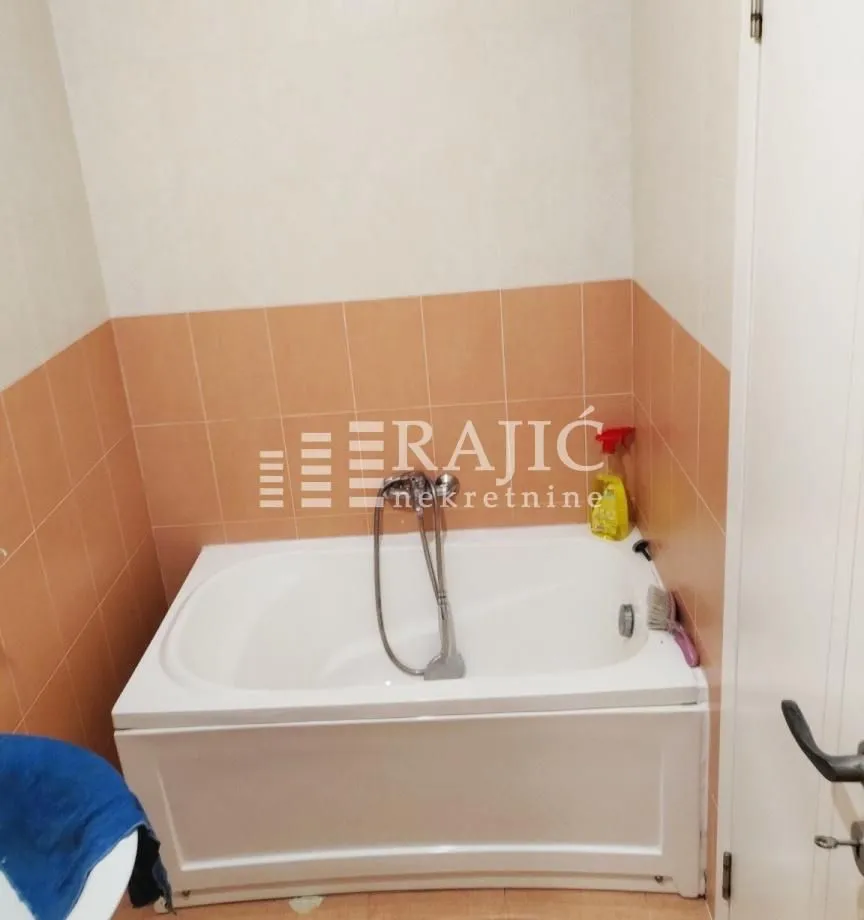 Small bathroom with a bathtub and light-toned ceramic tiles.