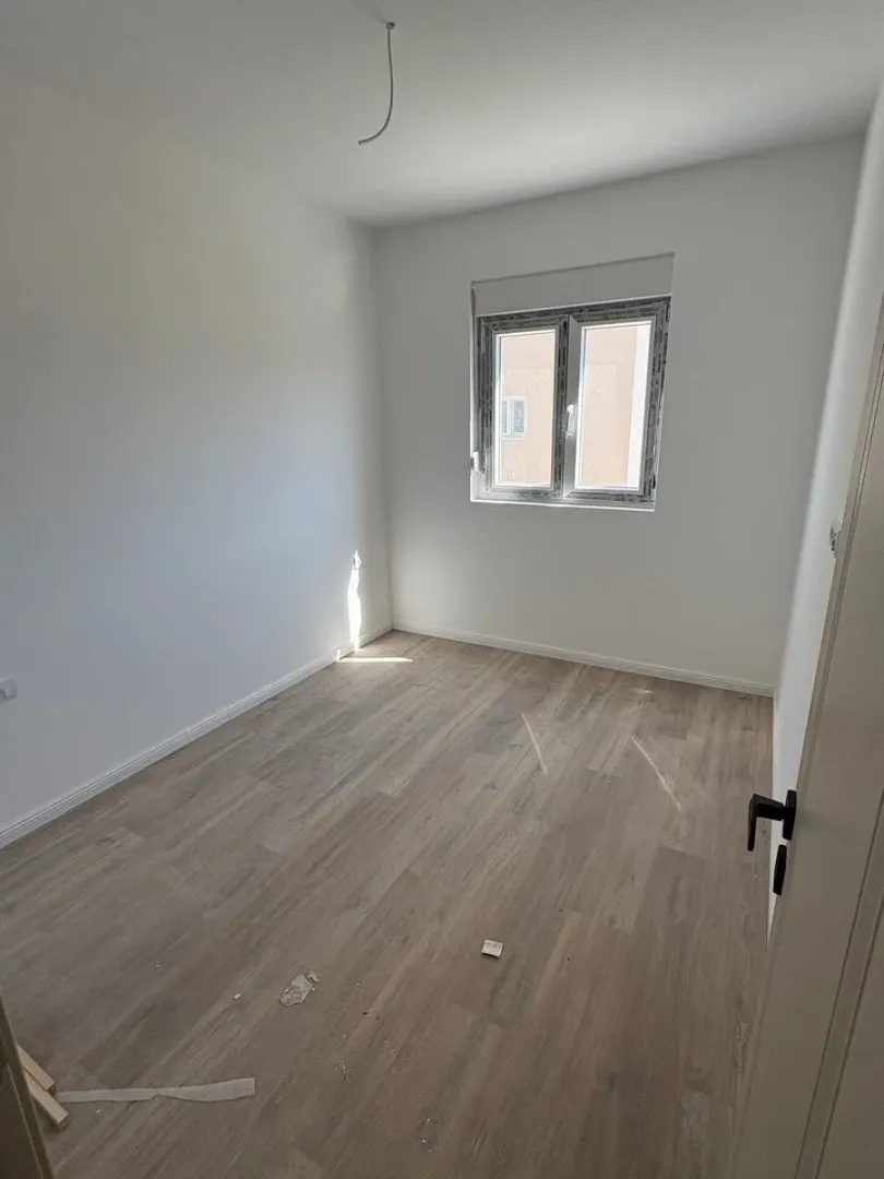 Prazna soba sa laminatom i bijelim zidovima.