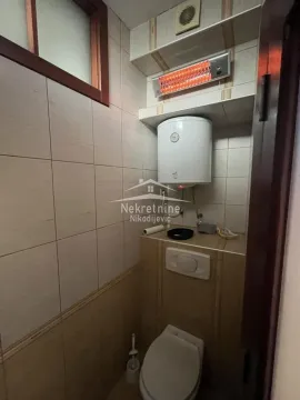 Smaller bathroom with a toilet, water heater, and wall heater. - image 17