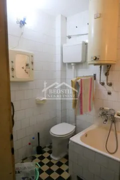 Manje kupatilo sa kadom, toaletom i bojlerom obloženo belim pločicama. - image 9