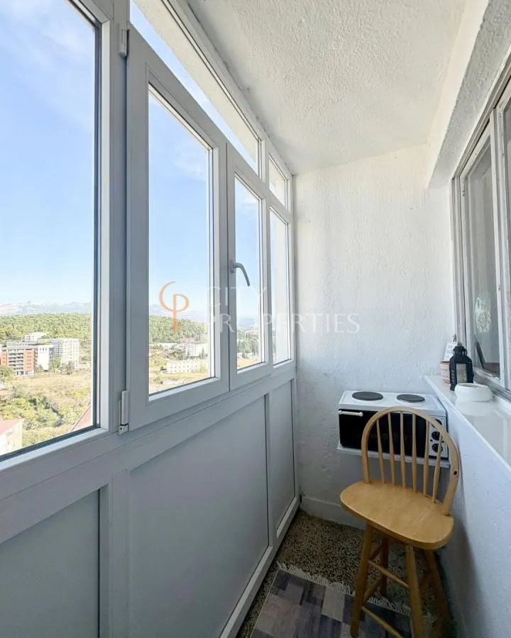 Zastakljeni balkon sa stolicom i pogledom na okolinu.
