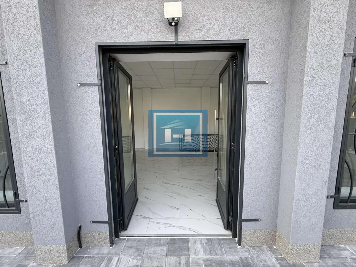 Entrance to a commercial space with glass doors and a paved sidewalk in front.