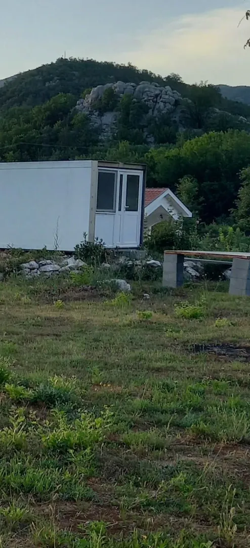 Montažni objekat u prirodi sa brdima u pozadini.