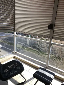 A balcony with a glass railing, shutters, and a view of the street. - image 21