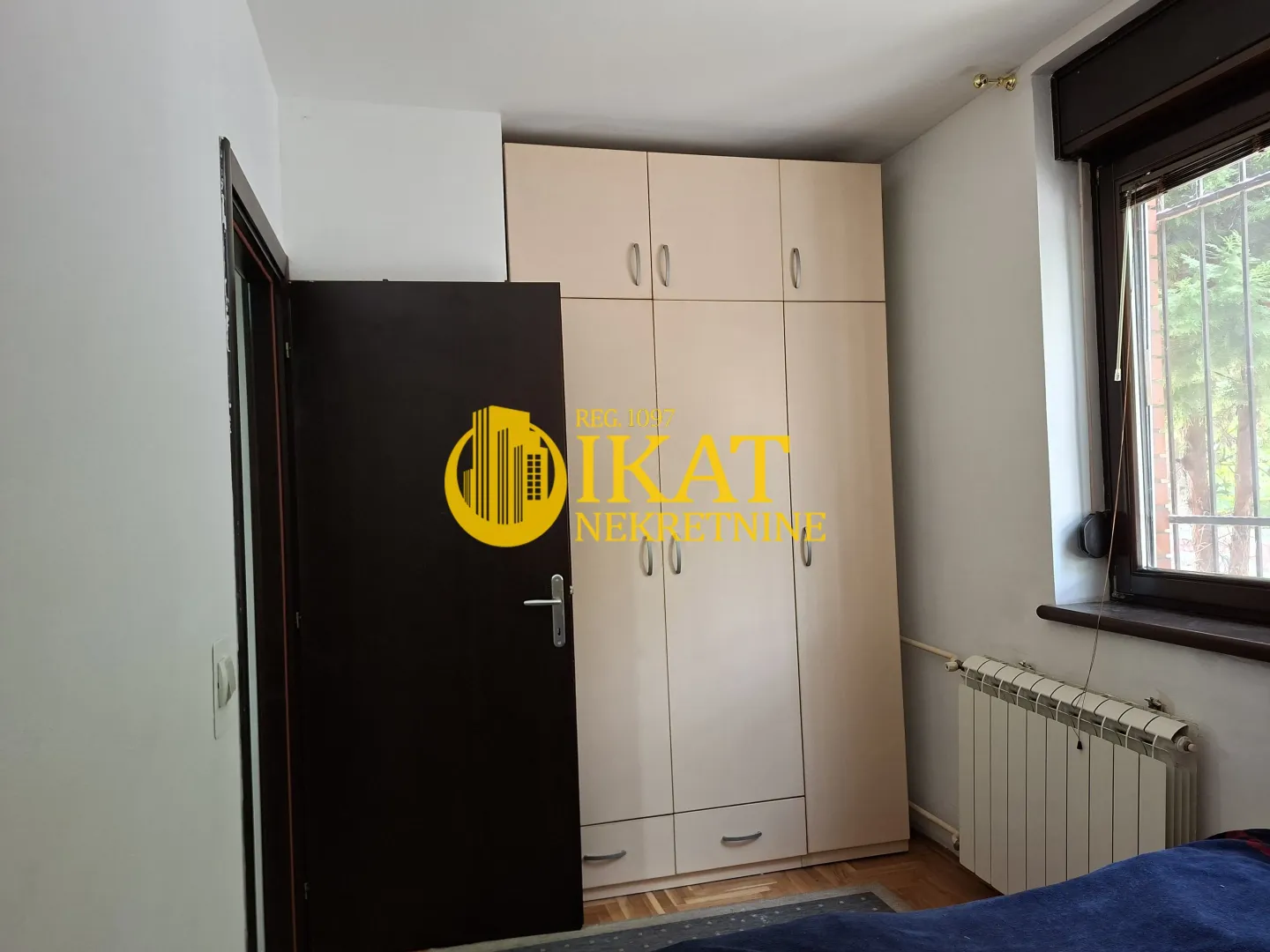 Manja spavaća soba sa ugradnim ormarom i prozorom.