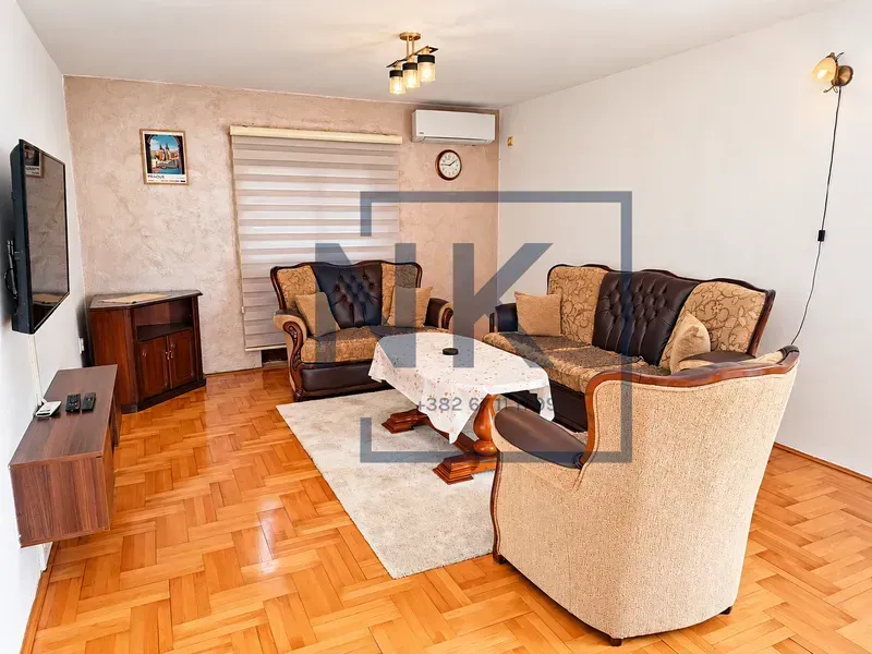 Furnished living room with a sofa set, wooden flooring, and a television.